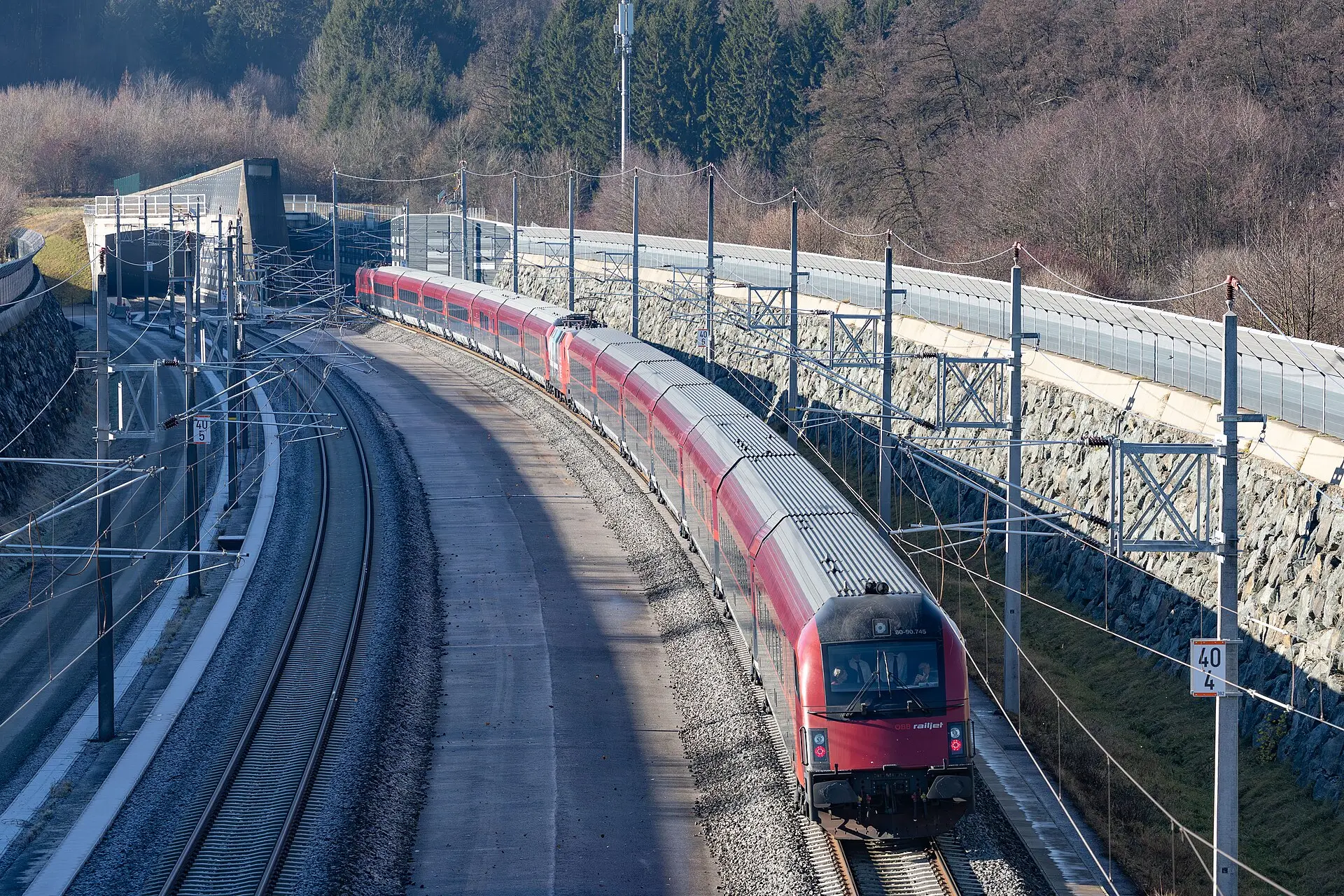 Premierenfahrt am Koralmtunnel: ein roter ÖBB-Railjet erreicht am 12. Dezember 2025 das Ostportal des Tunnels und fährt auf der zweigleisigen Neubaustrecke durch den Einschnitt